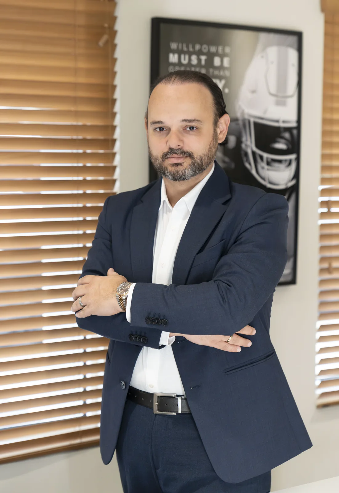 Studio portrait of Alvaro Wilson, standing in an office with his arms crossed