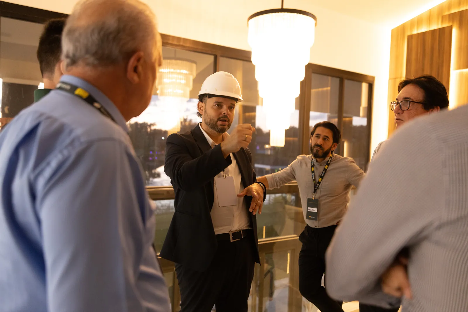 A presenter in a hard hat explaining a detail of the property to a small group