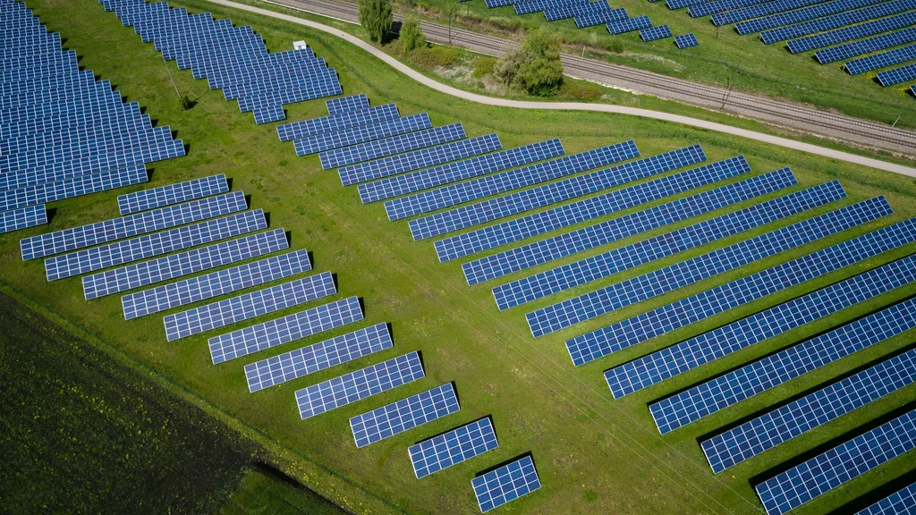 Aerial view of a solar panel farm on green fields
